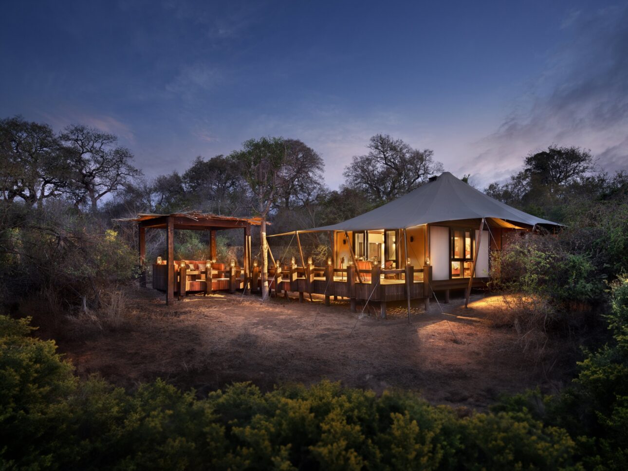 Tienda de lujo iluminada al atardecer durante un safari de lujo en África.