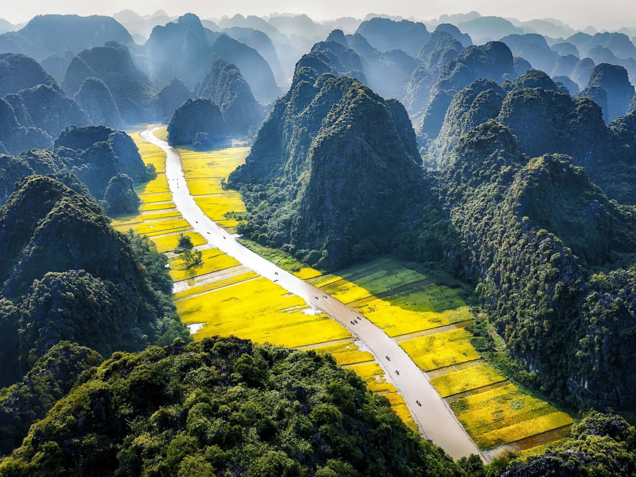 Paisaje de Ninh Binh en Vietnam, uno de los destinos culturales donde viajar en diciembre 2025, con río serpenteante, arrozales dorados y montañas kársticas.